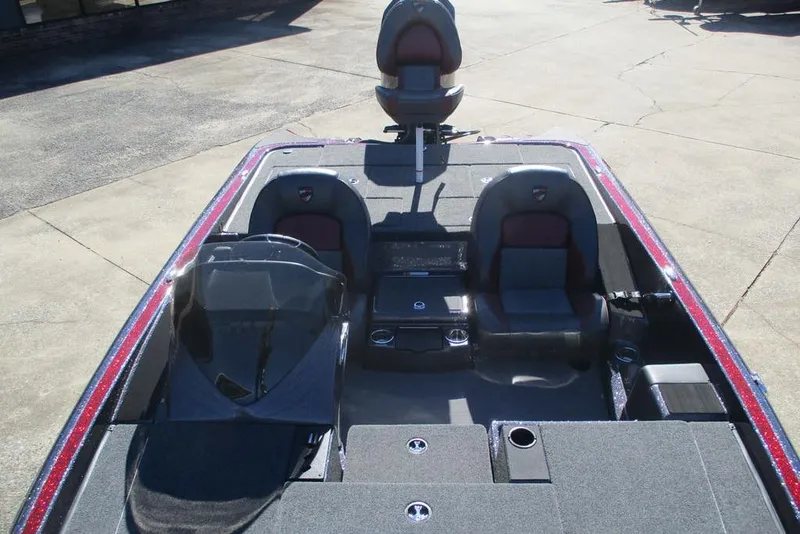 Slide: The Image of 2025 Triton 19 TrX Patriot boat interior with seating and console, parked on concrete. - 5