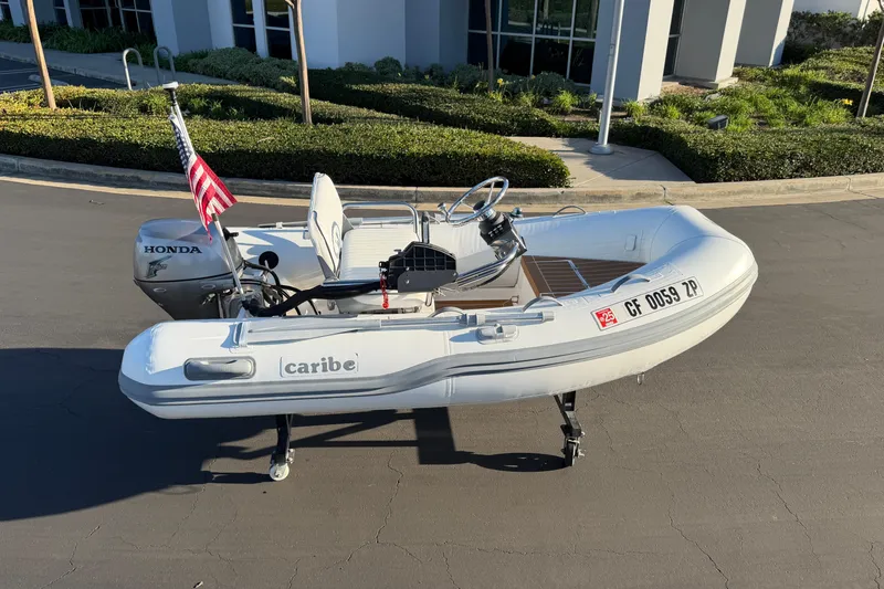 Slide: The Image of 2014 Caribe C10X inflatable boat with Honda motor, parked outdoors. - 10
