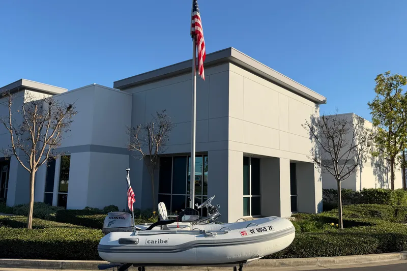 Slide: The Image of 2014 Caribe C10X inflatable boat with Honda motor, parked outside modern building. - 12