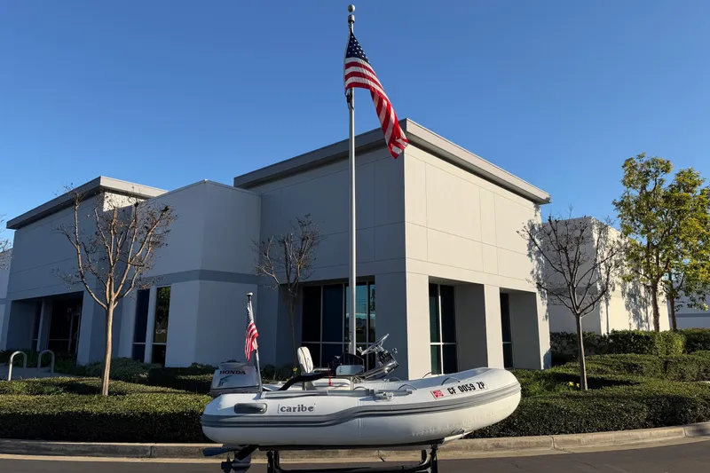Slide: The Image of Inflatable Caribe C10X boat, 2014 model, displayed outside modern building with American flag. - 13