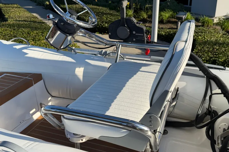 Slide: The Image of Steering console of a 2014 Caribe C10X boat with white seating and chrome details. - 4