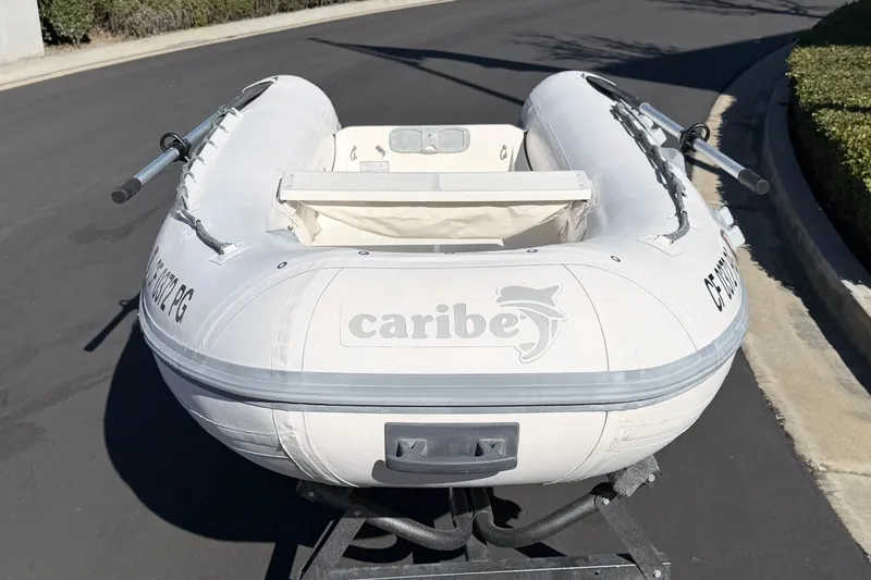 Slide: The Image of Inflatable Caribe C10X boat from 1999 on a trailer, parked on a street. - 3