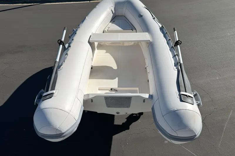 Slide: The Image of Inflatable boat on pavement, Caribe C10X 1999 model, featuring oars and seating. - 7
