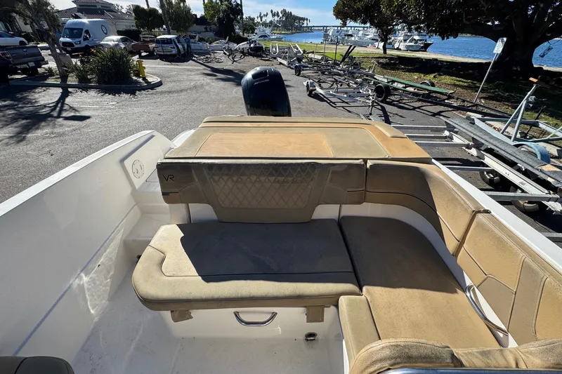 Slide: The Image of 2022 Bayliner VR6 Bowrider OB interior with tan seating, parked near waterfront. - 19