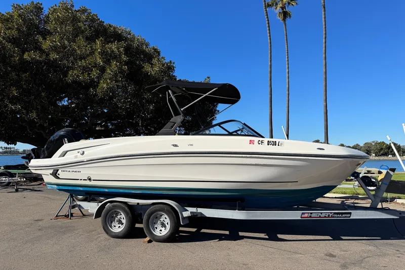 Slide: The Image of 2022 Bayliner VR6 Bowrider OB on trailer, parked near a lake with trees. - 2