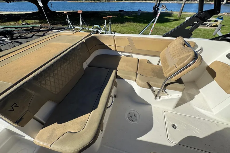 Slide: The Image of 2022 Bayliner VR6 Bowrider OB interior with tan seating, near a waterfront setting. - 22