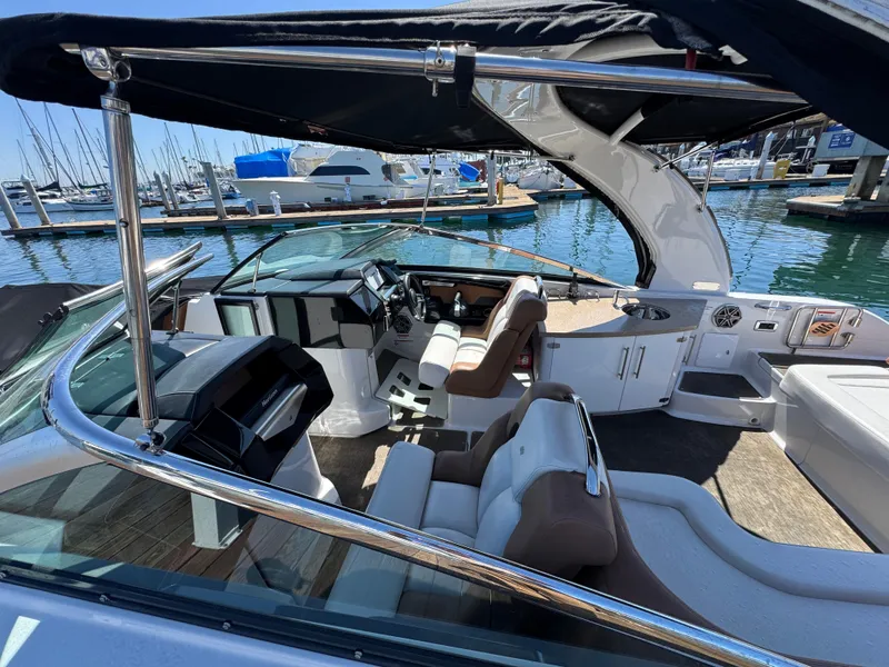 Slide: The Image of 2018 Four Winns H290 OB boat interior with seating, helm, and marina background. - 11