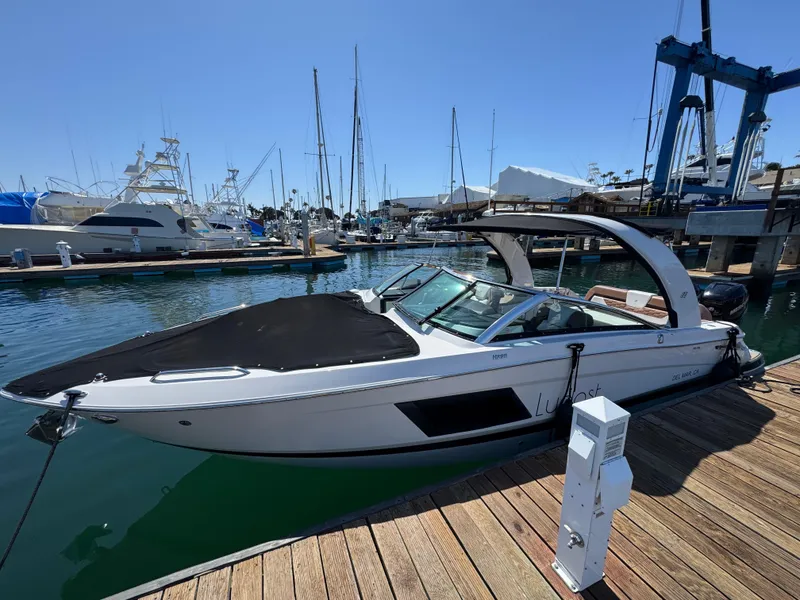 Slide: The Image of 2018 Four Winns H290 OB boat docked at marina with sailboats in background. - 13