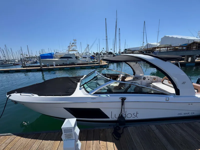 Slide: The Image of 2018 Four Winns H290 OB boat docked at marina with sailboats in background. - 14