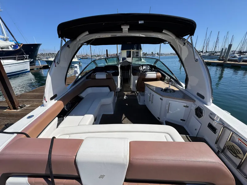 Slide: The Image of 2018 Four Winns H290 OB boat interior with spacious seating and sleek design at a marina. - 15