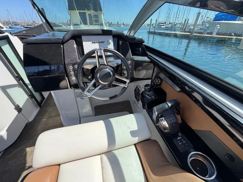 Slide: The Image of 2018 Four Winns H290 OB boat cockpit with steering wheel and controls, docked at marina. - 16