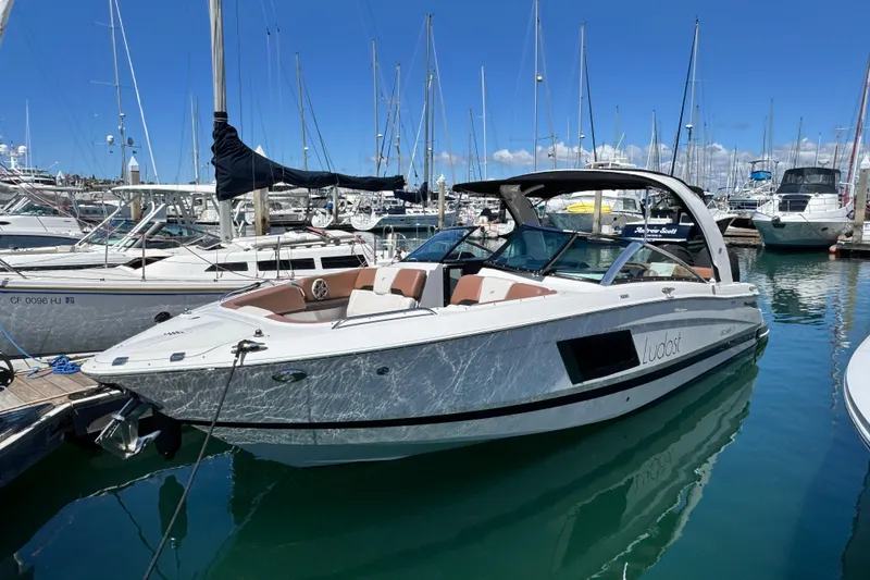 Slide: The Image of 2018 Four Winns H290 OB boat docked in a marina under clear blue skies. - 25