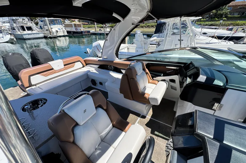 Slide: The Image of 2018 Four Winns H290 OB boat interior with luxurious seating and helm, docked at marina. - 26