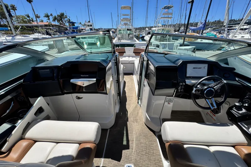 Slide: The Image of 2018 Four Winns H290 OB boat interior with dual consoles and luxurious seating at a marina. - 33