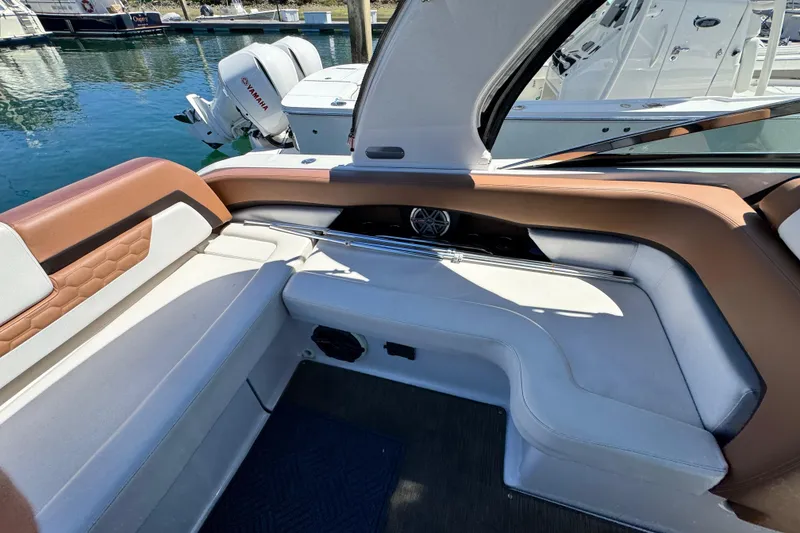 Slide: The Image of 2018 Four Winns H290 OB boat interior with white and brown seating, docked by water. - 39