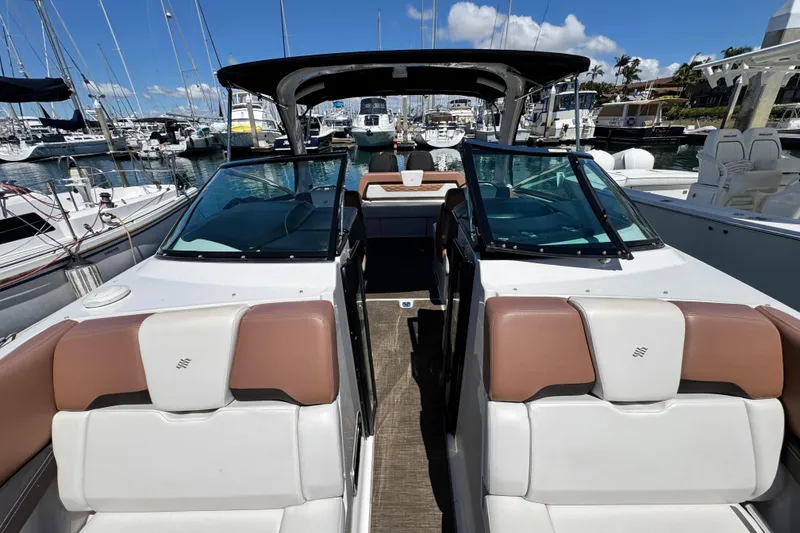 Slide: The Image of 2018 Four Winns H290 OB boat interior at marina, featuring sleek seating and windshield. - 41