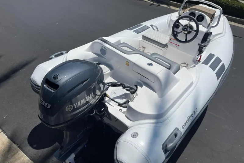 Slide: The Image of 2025 Caribe DL11 inflatable boat with Yamaha outboard motor, steering console, and seating. - 10