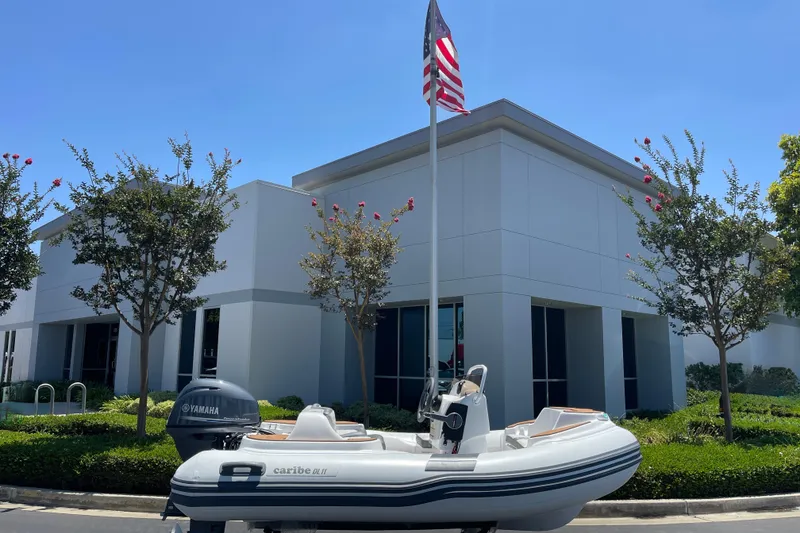 Slide: The Image of Inflatable Caribe DL11 boat with Yamaha motor outside modern building, 2025 model. - 20