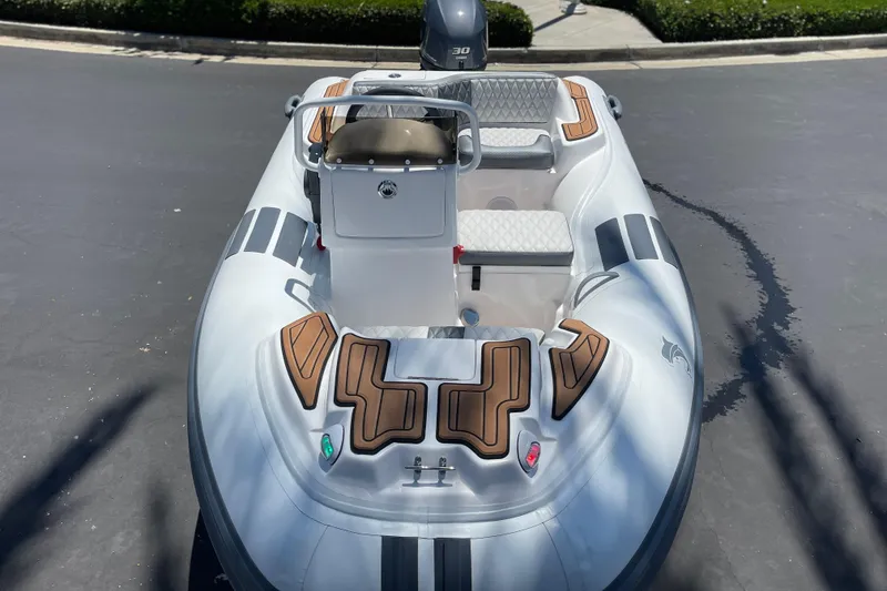 Slide: The Image of 2025 Caribe DL11 inflatable boat with seating and console, parked on pavement. - 33