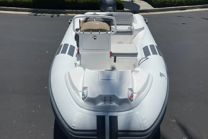 Slide: The Image of 2025 Caribe DL11 inflatable boat with seating, parked on pavement. - 5