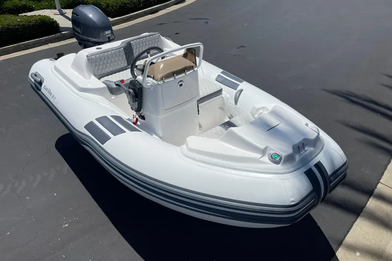 Slide: The Image of 2025 Caribe DL11 inflatable boat with Yamaha outboard motor on pavement. - 7