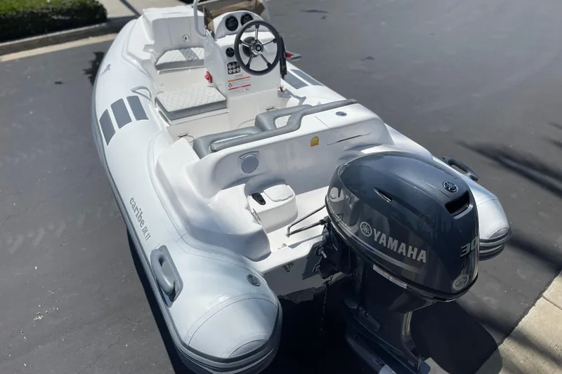 Slide: The Image of 2025 Caribe DL11 inflatable boat with Yamaha outboard motor, parked on pavement. - 8