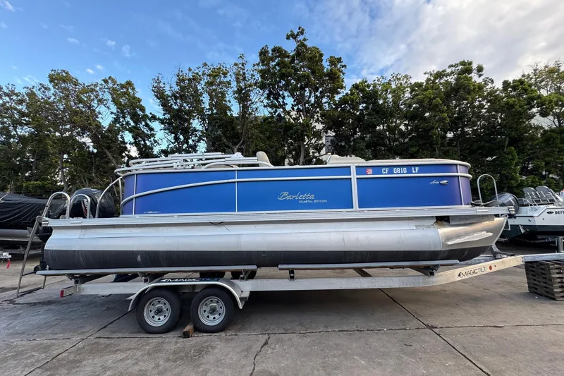 Slide: The Image of 2023 Barletta ARIA 22QC pontoon boat on trailer, blue exterior, parked outdoors. - 1