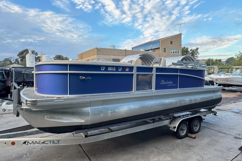 Slide: The Image of 2023 Barletta ARIA 22QC pontoon boat on trailer, blue exterior, parked outdoors. - 7