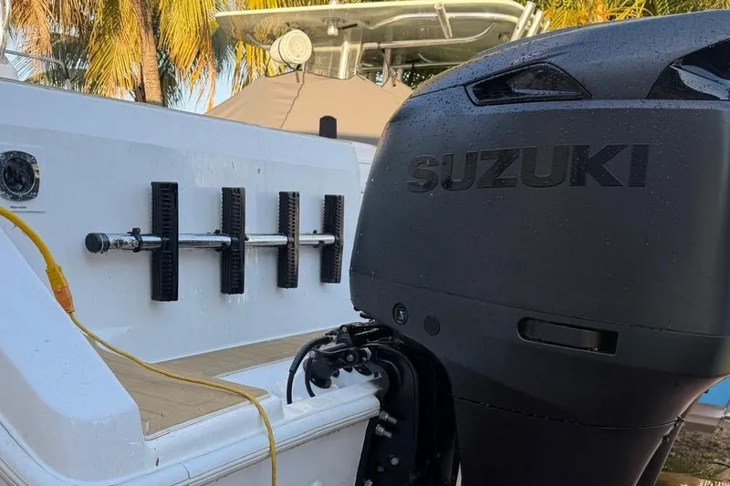 Slide: The Image of Century 3100 Walk-Around boat with Suzuki outboard motor, 2000 model, docked near palm trees. - 2