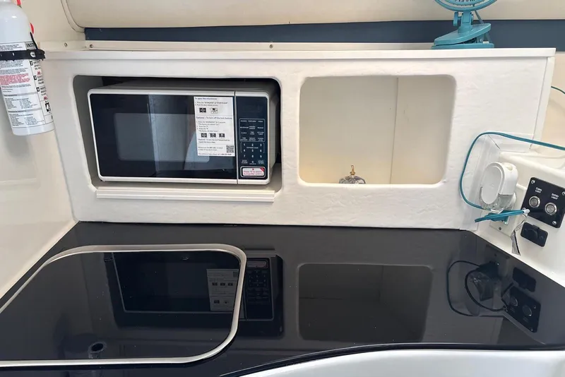 Slide: The Image of 2000 Century 3100 Walk-Around boat kitchen with microwave and black countertop. - 38