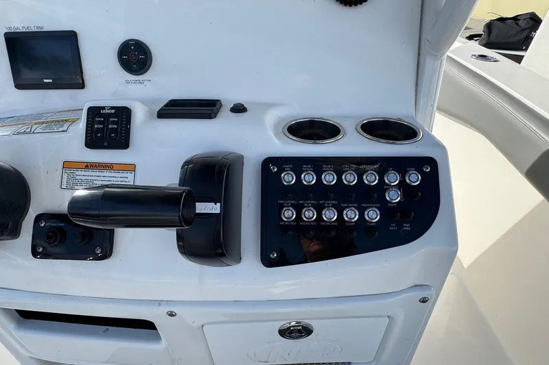 Slide: The Image of 2023 NauticStar 242L Offshore boat dashboard with controls and switches. - 17