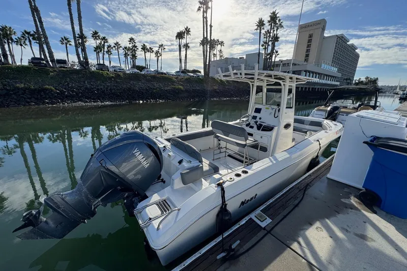 The Image of 2023 NauticStar 242L Offshore boat docked in a marina under clear blue skies. - 0