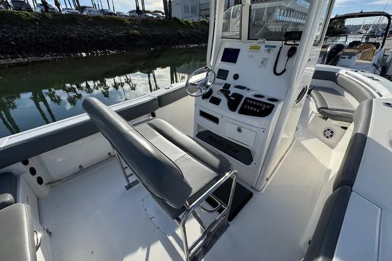 Slide: The Image of 2023 NauticStar 242L Offshore boat docked at marina under clear blue sky. - 13