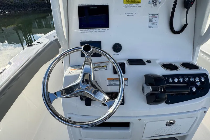 Slide: The Image of 2023 NauticStar 242L Offshore boat engine and deck by the water. - 18