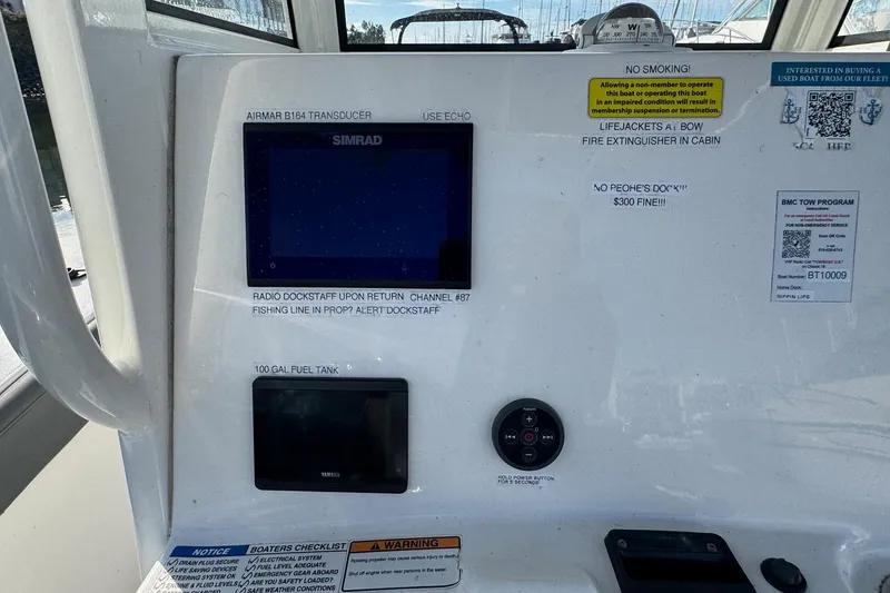 Slide: The Image of 2023 NauticStar 242L Offshore boat interior with seating and control panel at marina. - 20