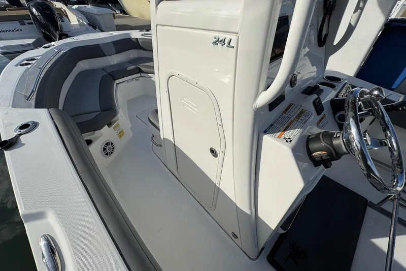 Slide: The Image of 2023 NauticStar 242L Offshore boat console with steering wheel and controls at marina. - 23