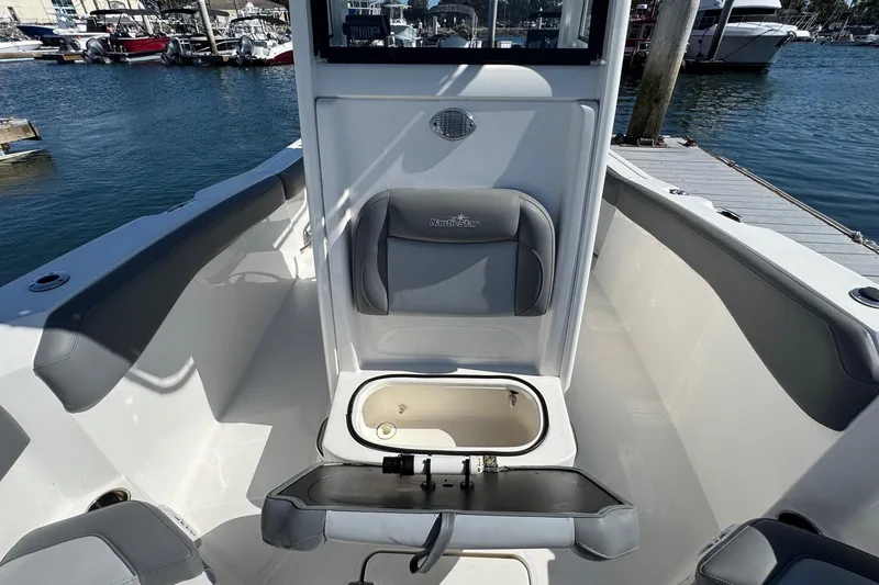 Slide: The Image of 2023 NauticStar 242L Offshore boat interior with seating and storage, docked at marina. - 33
