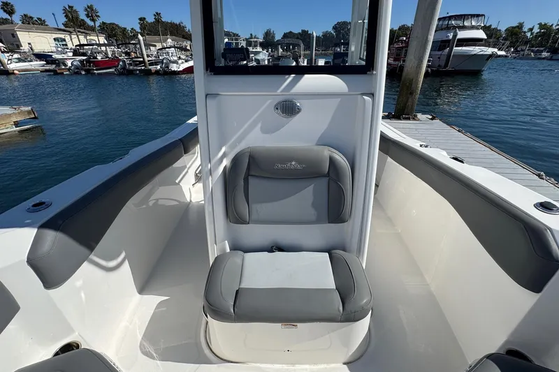 Slide: The Image of 2023 NauticStar 242L Offshore boat interior with seating, docked at marina. - 34