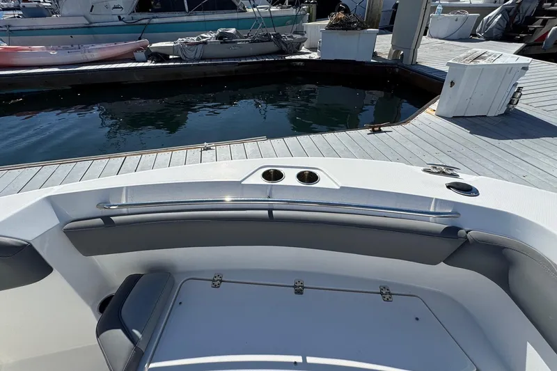 Slide: The Image of 2023 NauticStar 242L Offshore boat interior at dock, featuring seating and cup holders. - 37