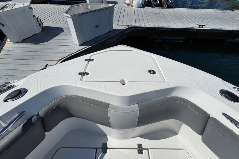 Slide: The Image of 2023 NauticStar 242L Offshore boat interior at dock, featuring seating and storage. - 38