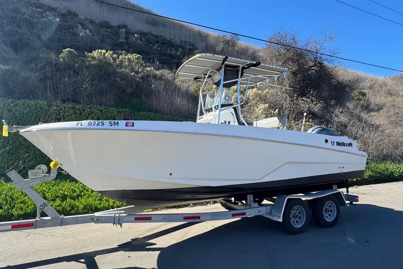 Slide: The Image of 2020 Wellcraft 222 Fisherman boat on trailer, parked on roadside with scenic background. - 4