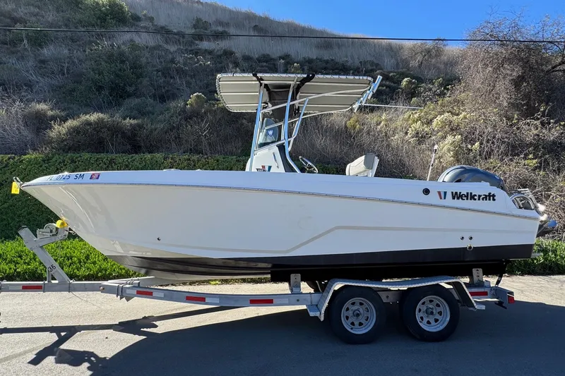 Slide: The Image of 2020 Wellcraft 222 Fisherman boat on trailer, parked outdoors with scenic background. - 5