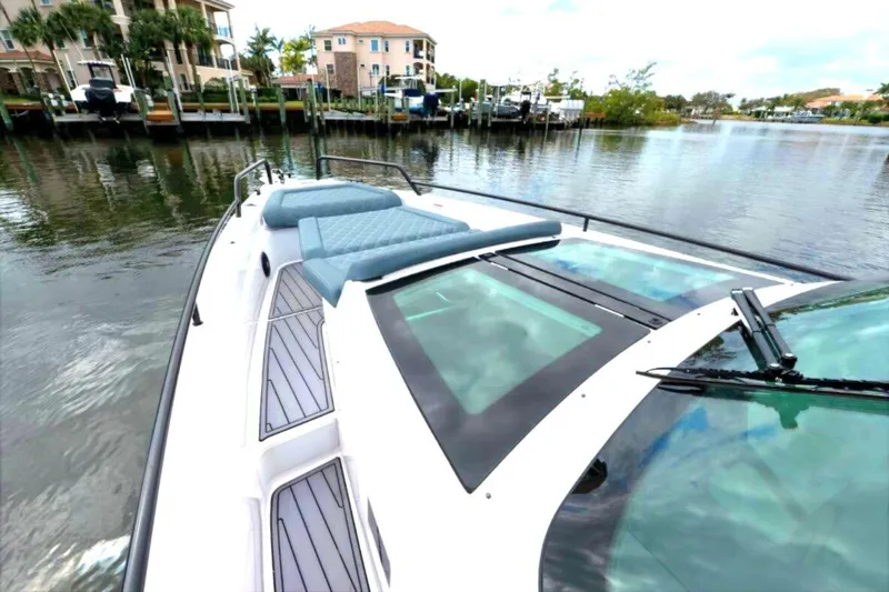 Slide: The Image of 2022 Axopar 37 Sun-Top boat with sunbed, docked in a scenic waterfront location. - 9