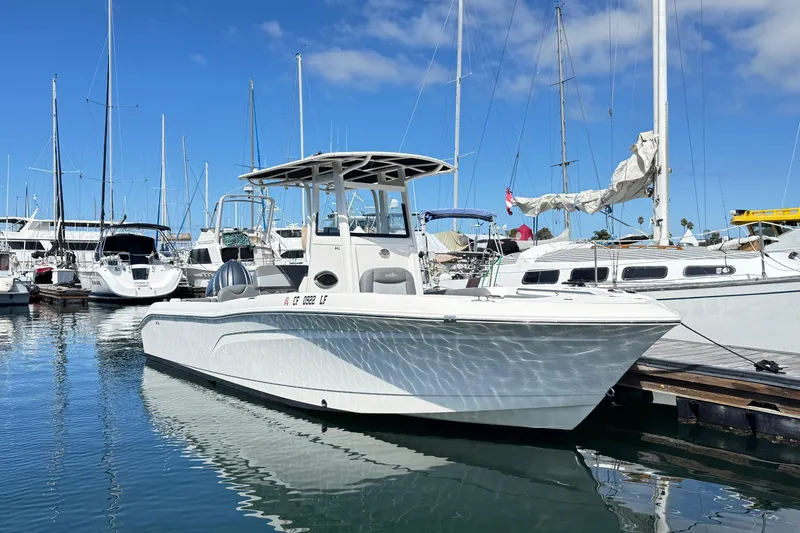 The Image of 2023 NauticStar 242L Offshore boat docked in a marina under clear blue skies. - 0