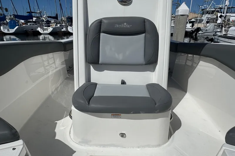 Slide: The Image of 2023 NauticStar 242L Offshore boat seat, gray upholstery, docked at marina. - 17