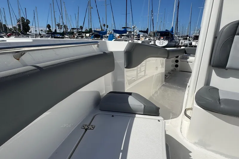 Slide: The Image of 2023 NauticStar 242L Offshore boat interior with gray seating, docked at marina. - 22