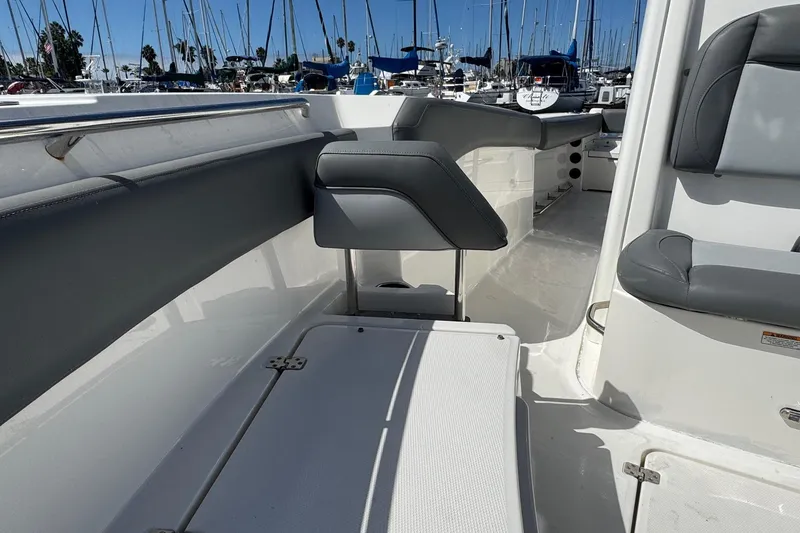 Slide: The Image of 2023 NauticStar 242L Offshore boat interior with seating and marina background. - 23