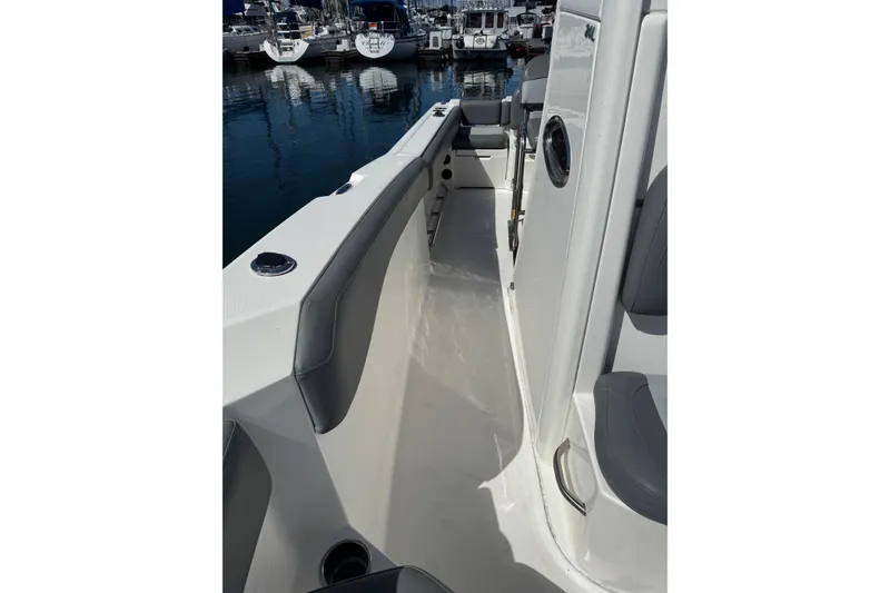 Slide: The Image of 2023 NauticStar 242L Offshore boat interior with seating, docked at marina. - 25