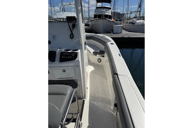 Slide: The Image of 2023 NauticStar 242L Offshore boat interior, docked at marina with other vessels. - 26