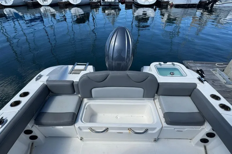 Slide: The Image of 2023 NauticStar 242L Offshore boat interior with seating and storage, docked at marina. - 27
